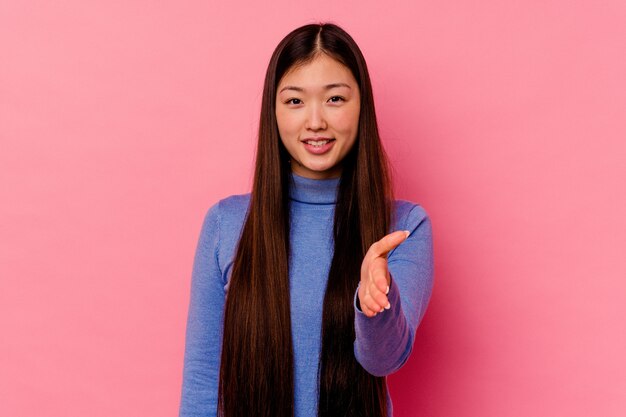 인사말 제스처에 손을 스트레칭 핑크에 고립 된 젊은 중국 여자.