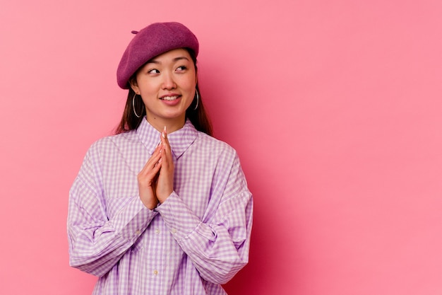 Young chinese woman isolated on pink wall making up plan in mind, setting up an idea.