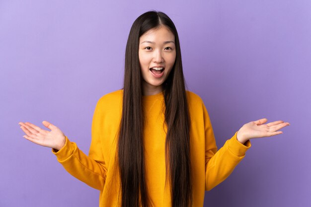 Young chinese woman over isolated purple wall with shocked facial expression