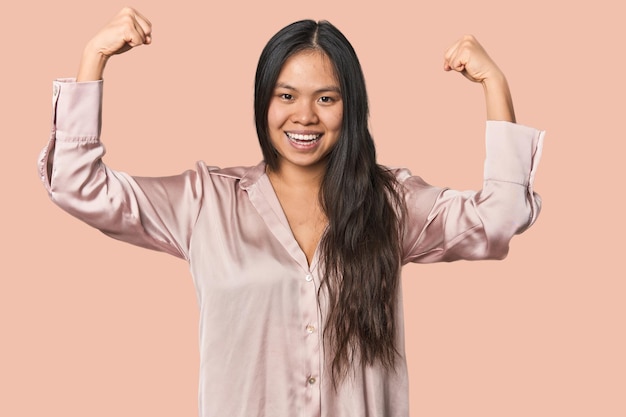 Young chinese woman isolated showing strength gesture with arms symbol of feminine power