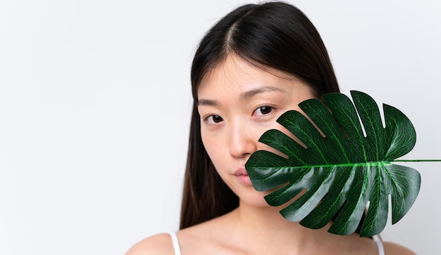 Young Chinese woman isolated on white background holding a palm leaf Close up portrait