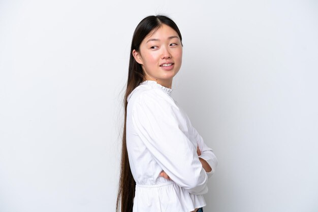 Young Chinese woman isolated on white background looking to the side and smiling