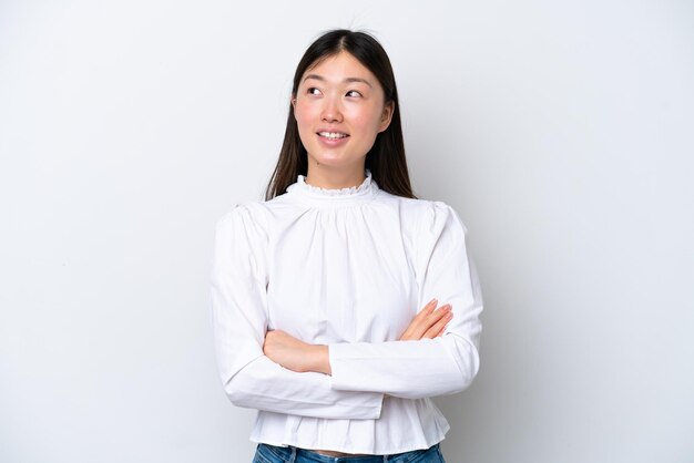 Young Chinese woman isolated on white background looking up while smiling