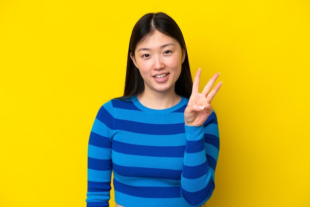 Young Chinese woman isolated on yellow background happy and counting three with fingers