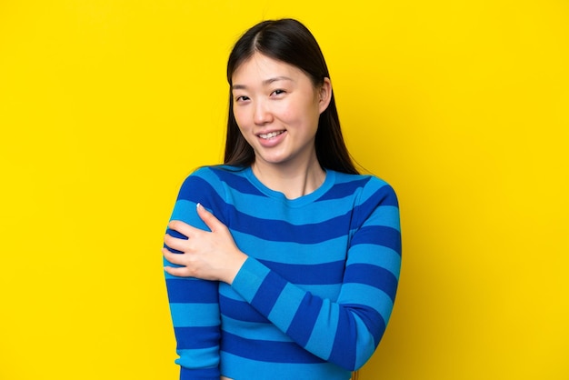 Young Chinese woman isolated on yellow background laughing