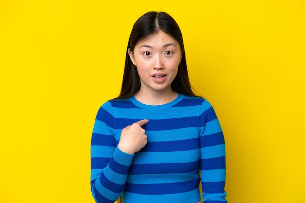 Young Chinese woman isolated on yellow background pointing to oneself