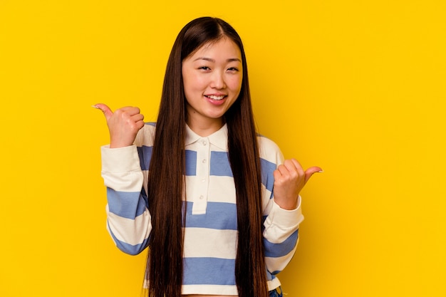 두 엄지 손가락을 제기, 미소와 자신감 노란색 배경에 고립 된 젊은 중국 여자.