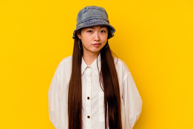 Young chinese woman isolated on yellow background sad, serious face, feeling miserable and displeased