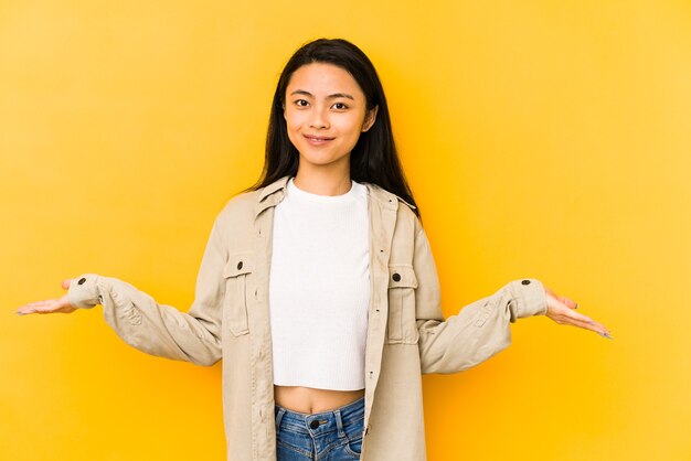 Young chinese woman isolated on a yellow background showing a welcome expression.