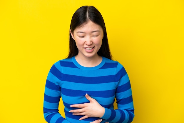 Young Chinese woman isolated on yellow background smiling a lot