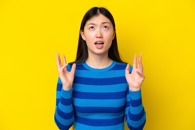 Young Chinese woman isolated on yellow background stressed overwhelmed