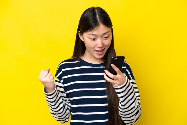 Young chinese woman isolated on yellow background surprised and sending a message