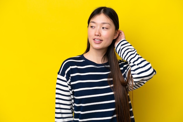 아이디어를 생각 하는 노란색 배경에 고립 된 젊은 중국 여자