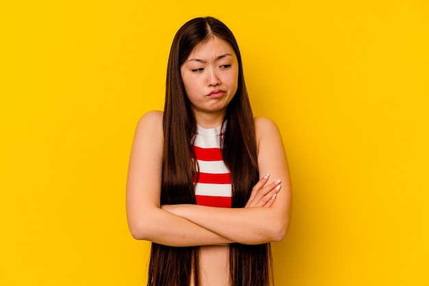 Young chinese woman isolated on yellow background tired of a repetitive task.