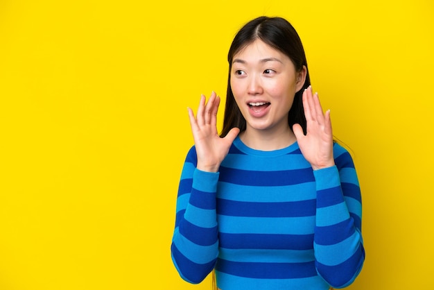 놀람 표정으로 노란색 배경에 고립 된 젊은 중국 여자