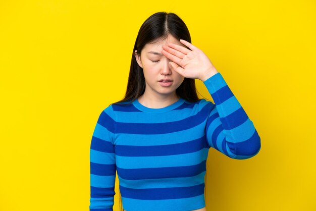 Young chinese woman isolated on yellow background with tired and sick expression