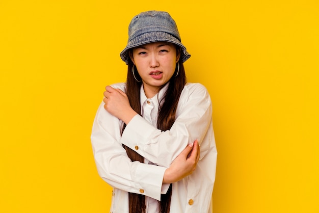 Young chinese woman isolated on yellow massaging elbow, suffering after a bad movement.