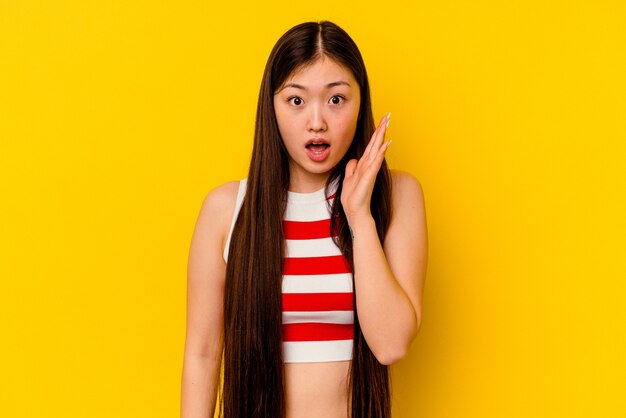 Young chinese woman isolated on yellow surprised and shocked.