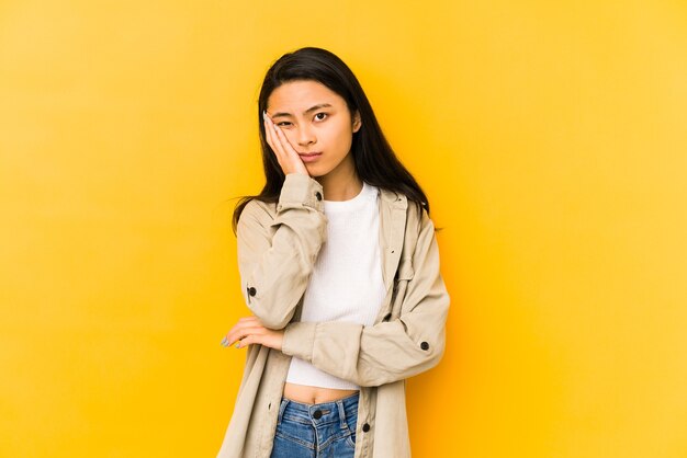 Young chinese woman isolated on a yellow wall who is bored, fatigued and need a relax day.
