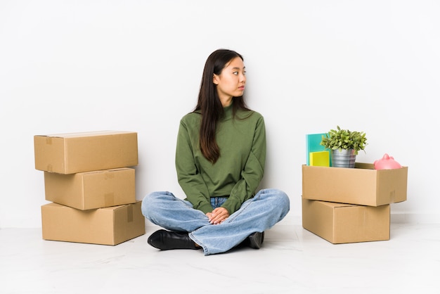 Young chinese woman moving to a new home gazing left, sideways pose.