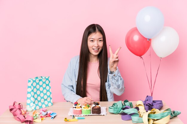 Young chinese woman organizing a birthday isolated showing number two with fingers.