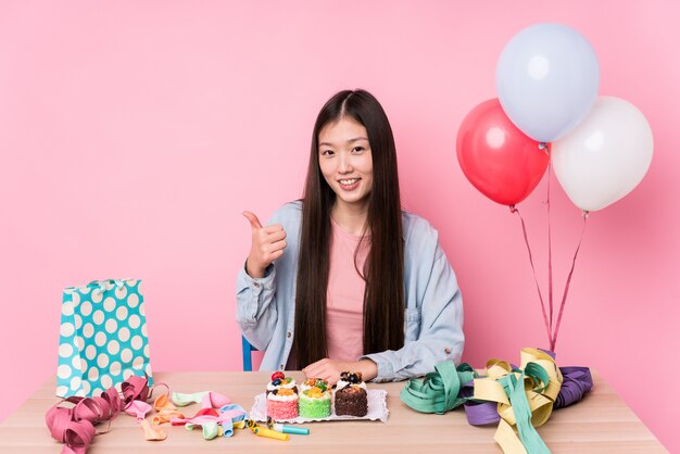 Young chinese woman organizing a birthday smiling and raising thumb up