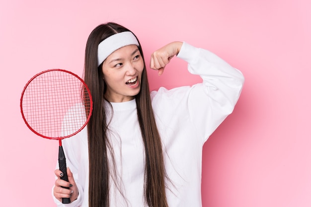 Young chinese woman playing badminton isolated raising fist after a victory, winner concept.