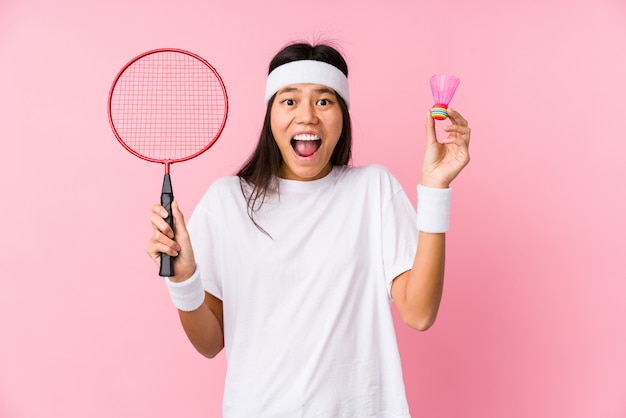 Young chinese woman playing badminton isolated