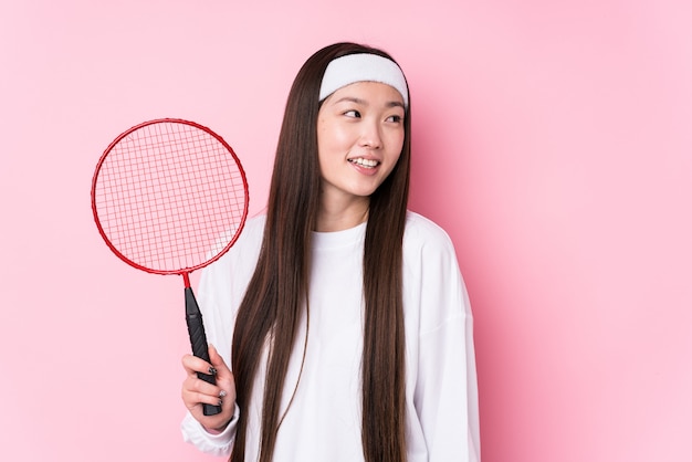 Young chinese woman playing badminton looks aside smiling, cheerful and pleasant.