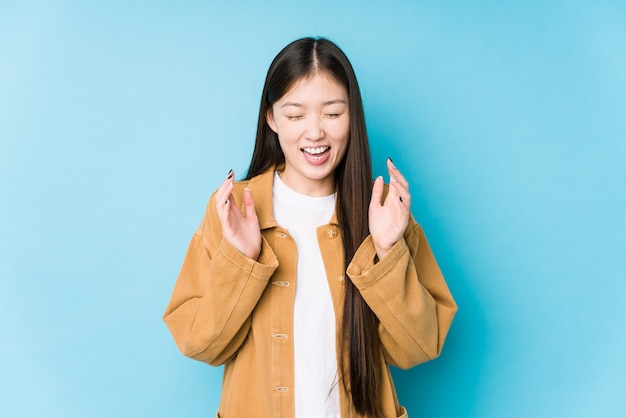 Young chinese woman posing in a blue wall joyful laughing a lot