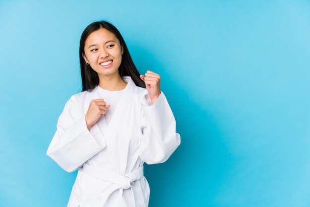 Young chinese woman practicing karate isolated raising fist after a victory, winner concept.