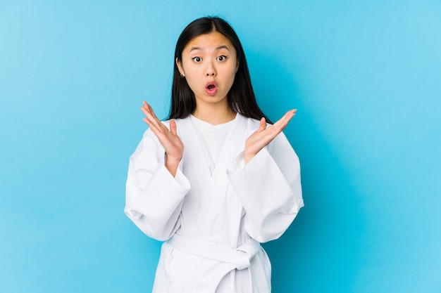 Young chinese woman practicing karate isolated surprised and shocked.