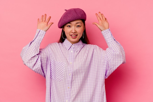 Young chinese woman   receiving a pleasant surprise, excited and raising hands.