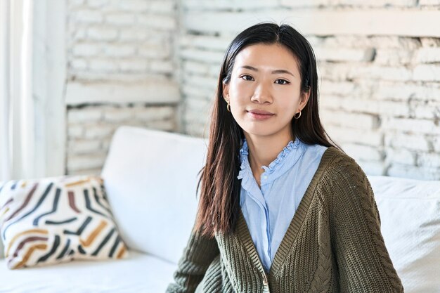 Young Chinese woman relaxes alone on her home sofa