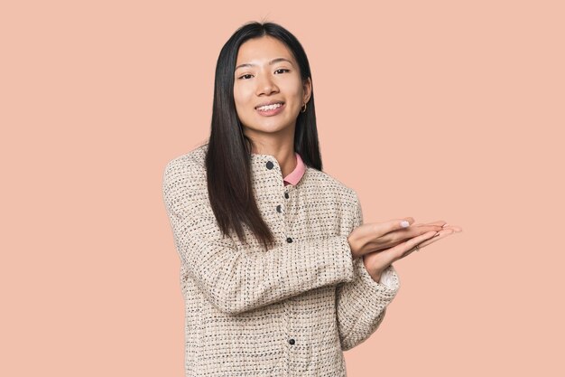 Photo young chinese woman in studio setting holding a copy space on a palm