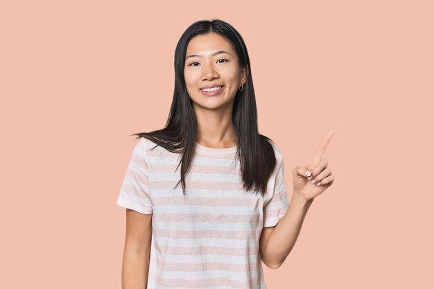 Young Chinese woman in studio setting showing number one with finger