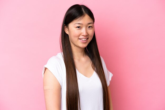 Young Chinese woman wearing a band aids isolated on pink background smiling a lot