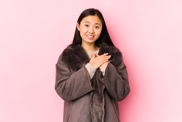孤立したコートを着た若い中国人女性は、手のひらを胸に押し付けて、優しい表情をしています。愛の概念。