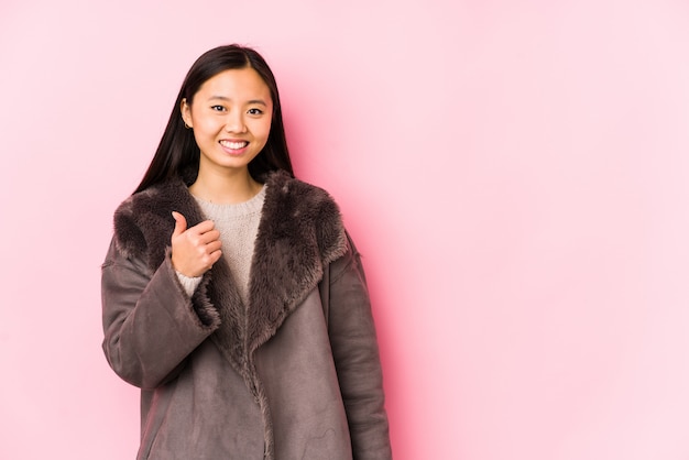 Young chinese woman wearing a coat isolated smiling and raising thumb up