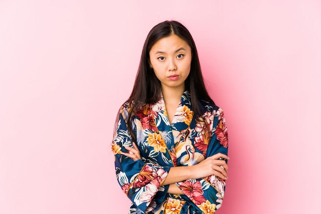 Young chinese woman wearing a kimono pajama isolated unhappy looking with sarcastic expression.