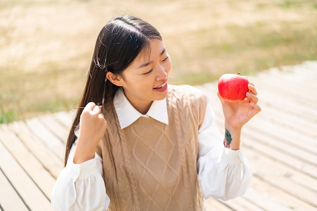 야외에서 승리를 축하하는 사과를 들고 있는 젊은 중국 여성