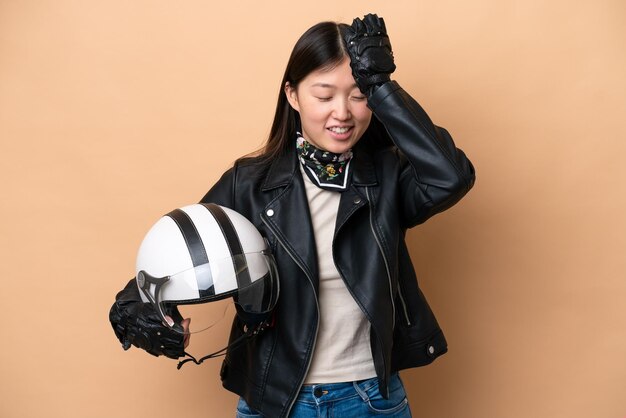 Young Chinese woman with a motorcycle helmet isolated on beige background has realized something and intending the solution