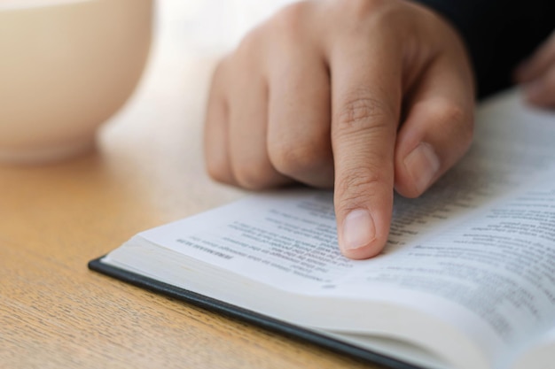 A young Christian woman sits and reads and studies the Bible with the teachings of the Prophet