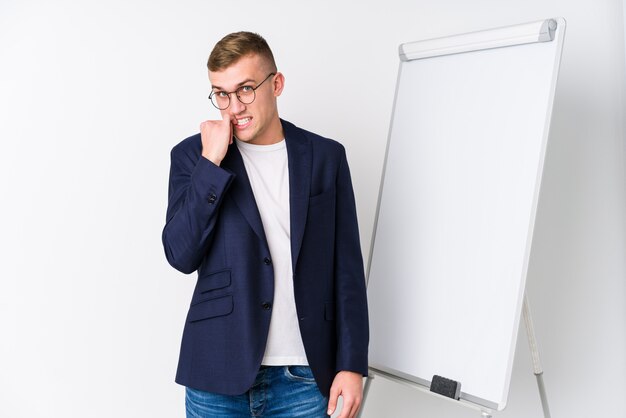 Young coaching man showing a white board biting fingernails, nervous and very anxious.