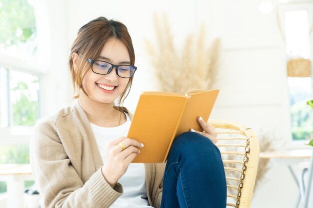 Giovane studente di collage che legge un libro seduto su una sediaxa