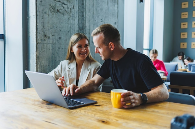 Photo young colleagues managers are sitting at the table and laughing concept of business cooperation and teamwork young smiling people at the table in the office with a laptop modern successful people