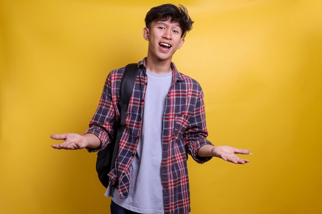 Young college student man wearing casual shirt and backpack over yellow background gesture showing p