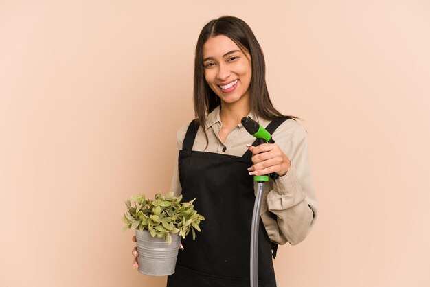 Young Colombian gardener holds a plant and hose, nurturing nature.