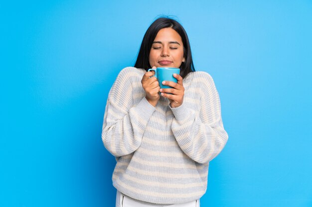 Young Colombian girl with sweater holding a hot cup of coffee