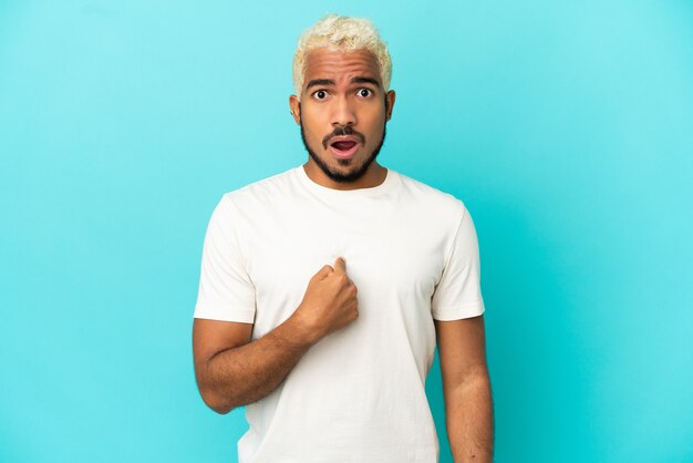 Young Colombian handsome man isolated on blue background pointing to oneself